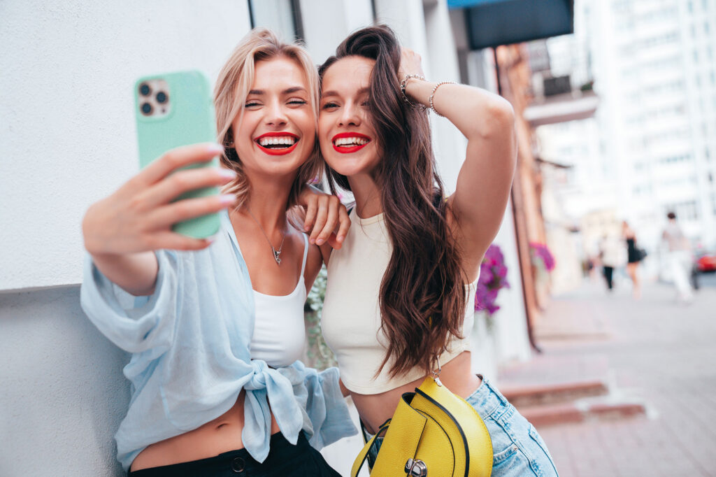 Zwei lachende junge Frauen machen ein Selfie.