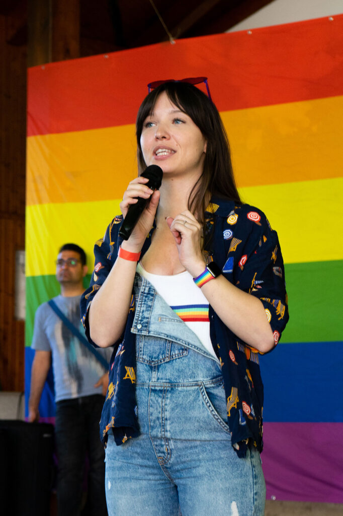 Anna Robosch in Regenbogen-Outfit bei einem Vortrag.