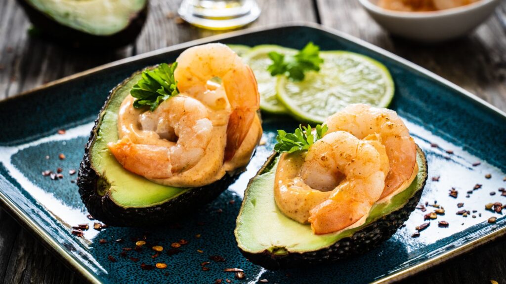 Grillrezepte: Zwei halbe Avocados gefüllt mit Garnelen auf einem blauen Teller.