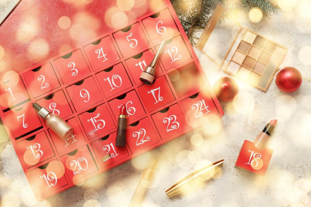 Roter Adventkalender mit einigen ausgepackten Kosmetik-Produkten liegt auf heller Oberfläche.