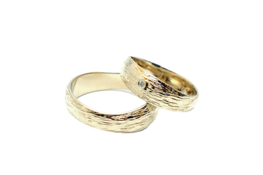 Zwei goldene Ringe mit Gravur liegen aufeinander