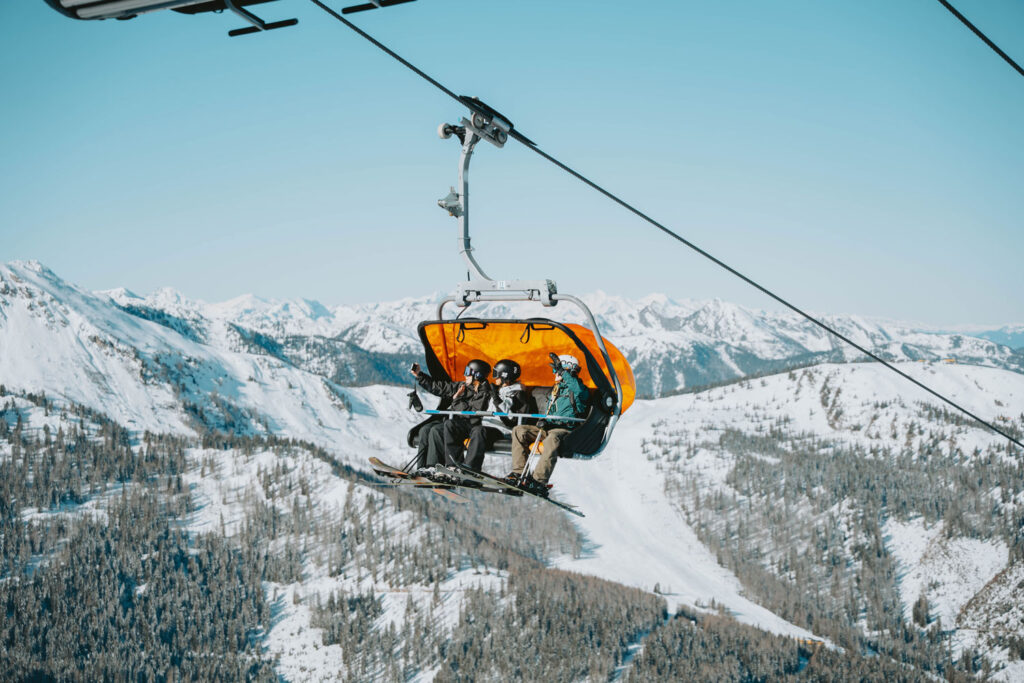 Skilift-Gondel mit drei Skifahrern in der Luft beim Natur- & Wellnesshotel Höflehner ****Superior in der Region Schladming-Dachstein.