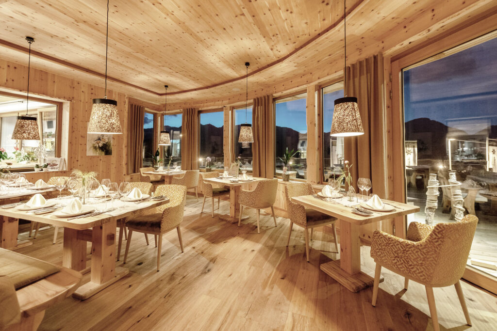 Hölzernes, hell beleuchtetes Restaurant am Abend mit bergiger Aussicht.