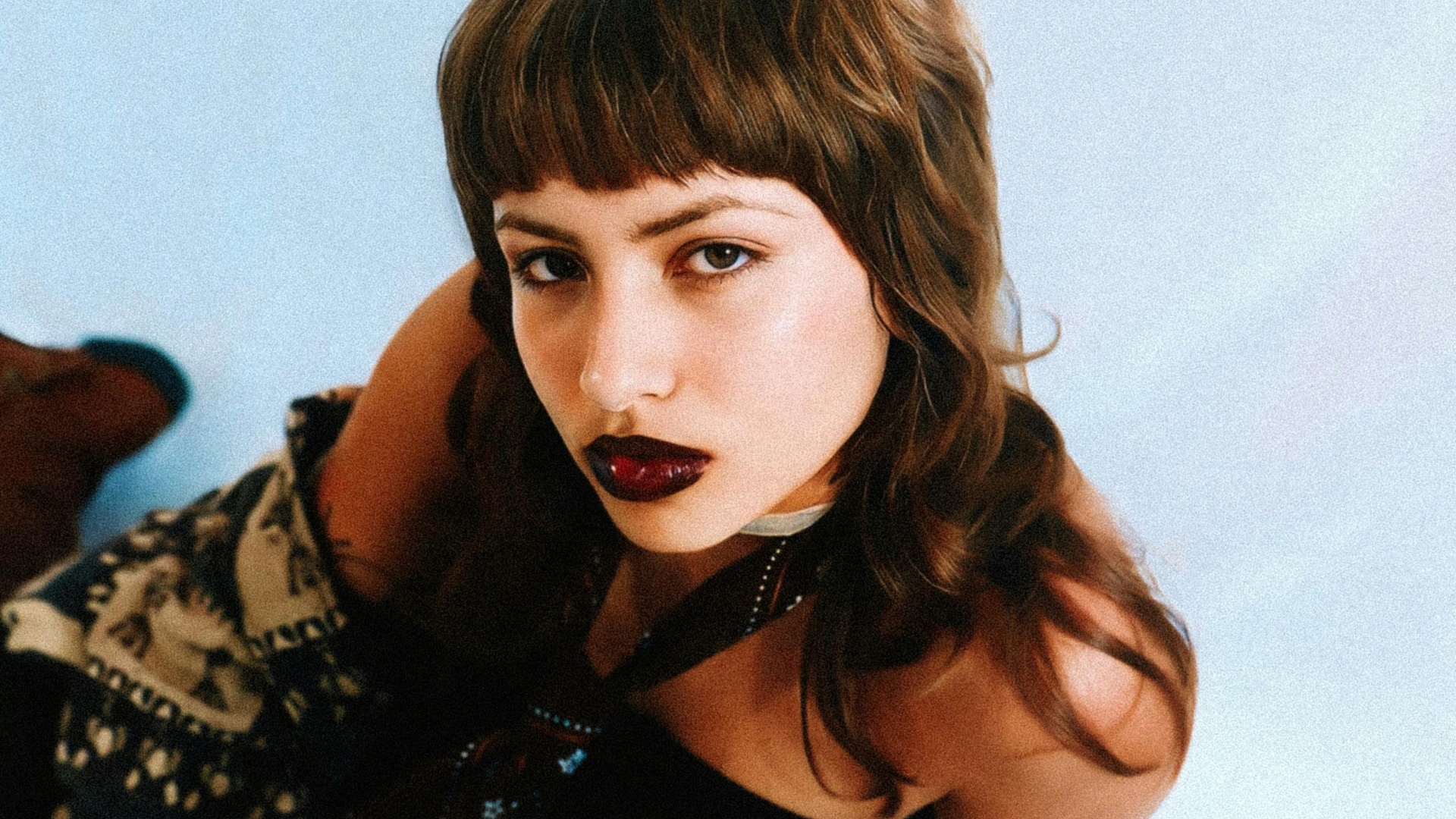 Frau mit dunkelroten Lippen und Mullet sitzt am Boden