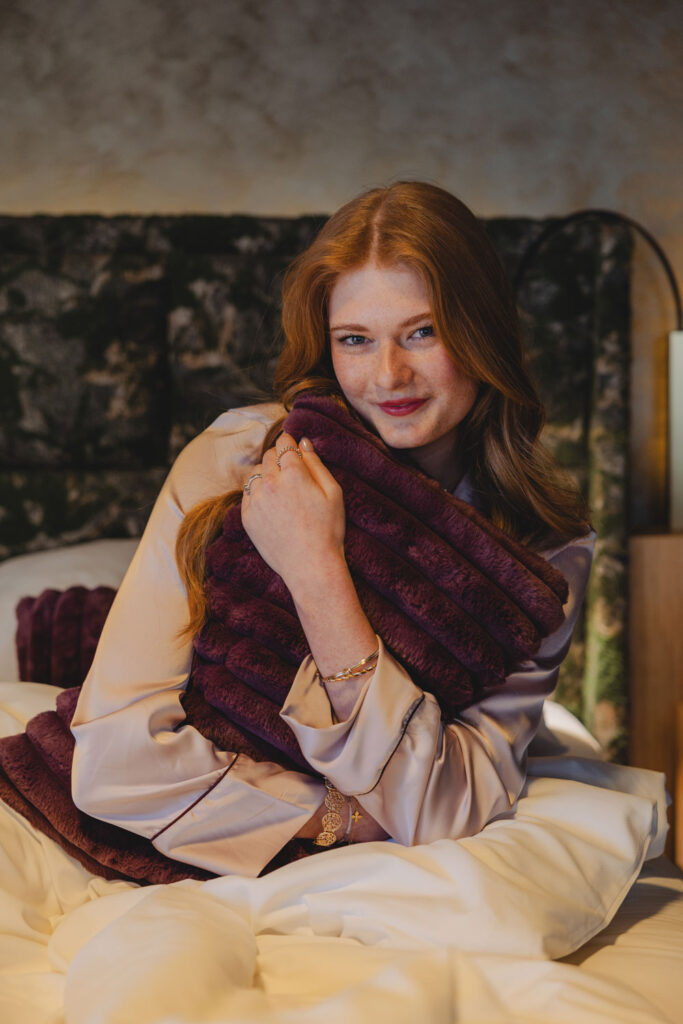 Frau umarmt flauschigen Polster in einem Bett.