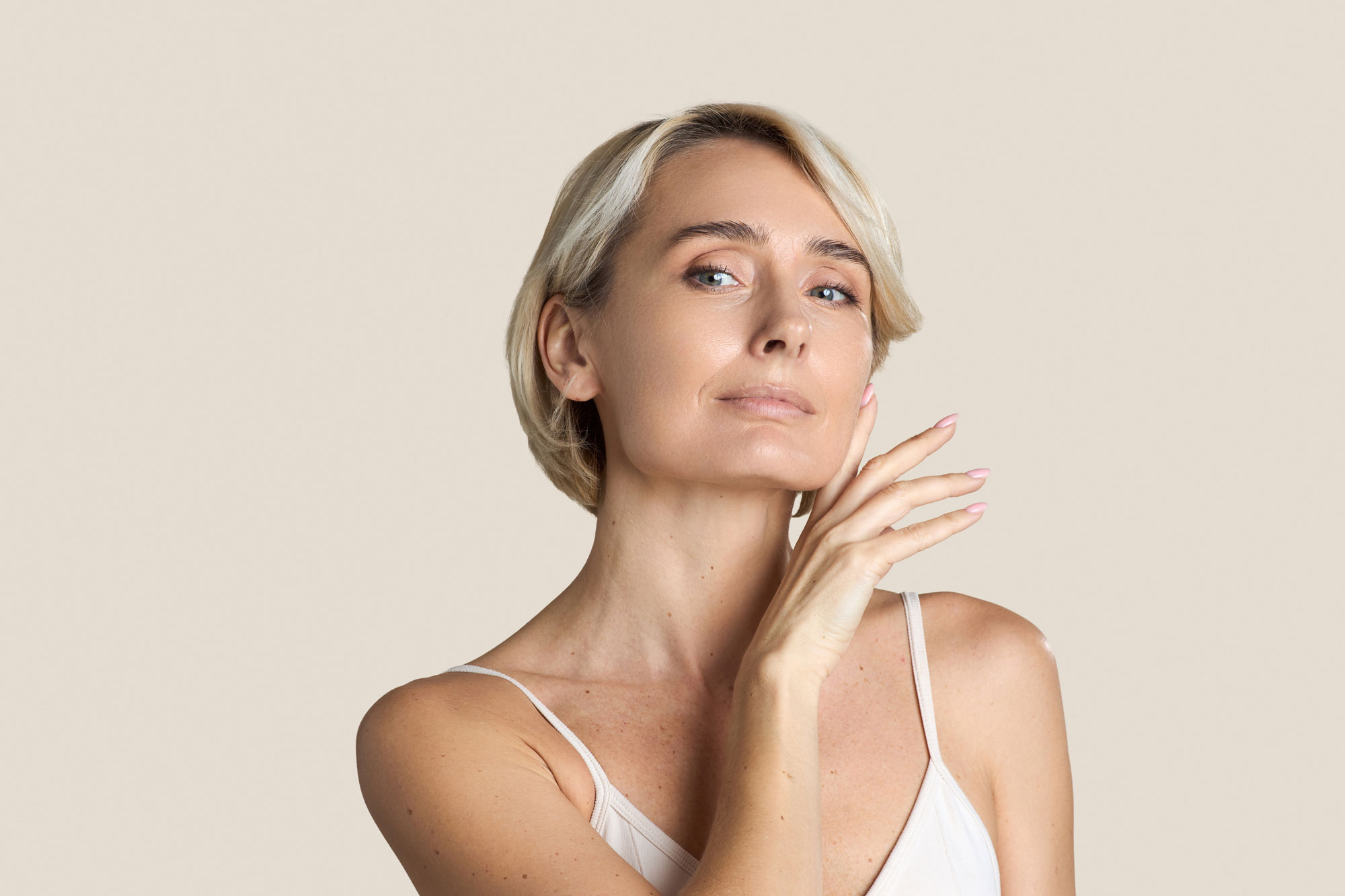 Frau mit kurzen blonden Haaren und glatter Haut im Gesicht.