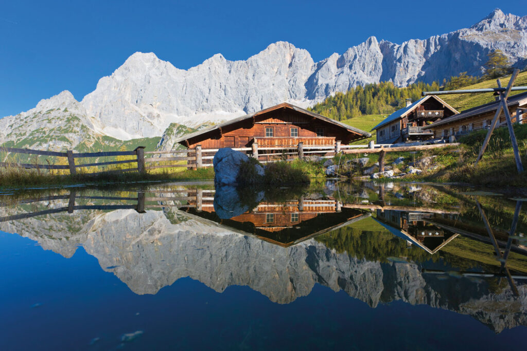 Hölzerne Häuser am See mit Bergen im Hintergrund