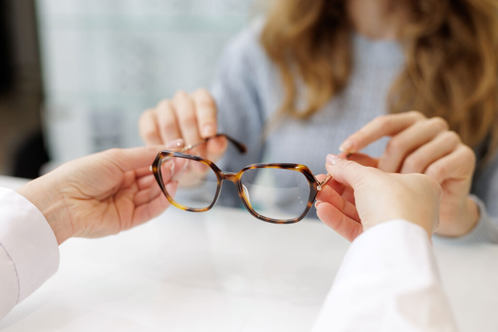 Optiker übergibt Brille an Kundin