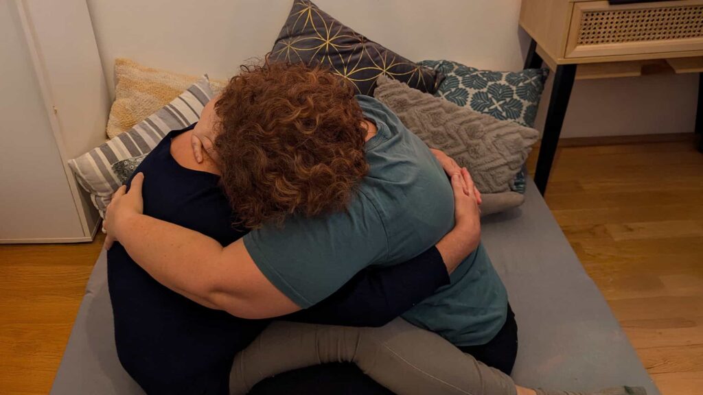 Zwei Menschen umarmen sich innig auf einer Couch.