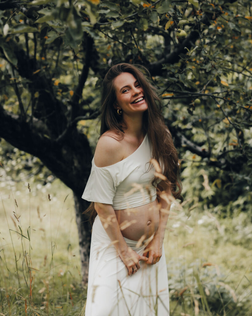 Lisa-Marie Schiffner schwanger in weißem Outfit vor einem Baum