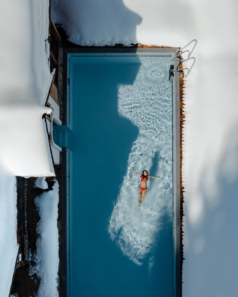 Frau schwimmt in Pool mit Schnee rundherum