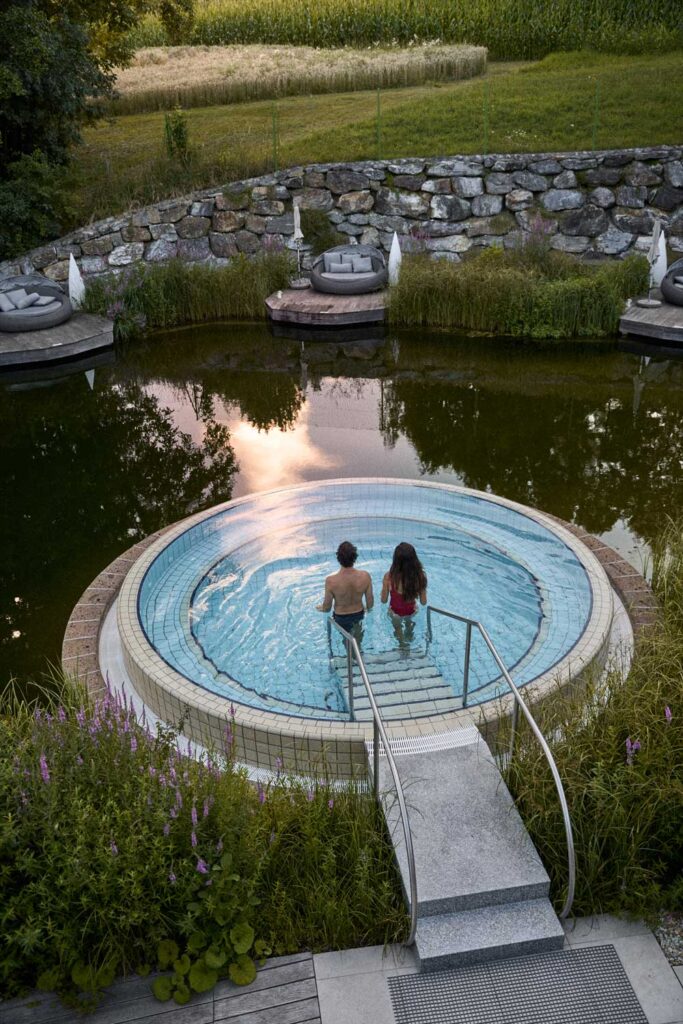 Ein Pärchen geht in einen runden Whirlpool mitten in einem Teich.