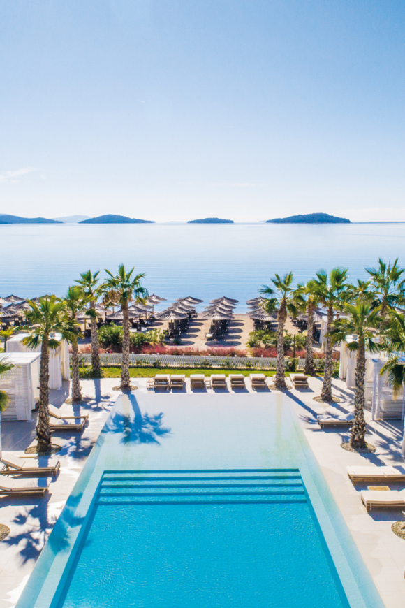 Gewinne ein Wochenende im Amadria Park Hotel Jure. Das Bild zeigt die Hotel-Poollandschaft umringt von Palmen mit Blick aufs Meer.