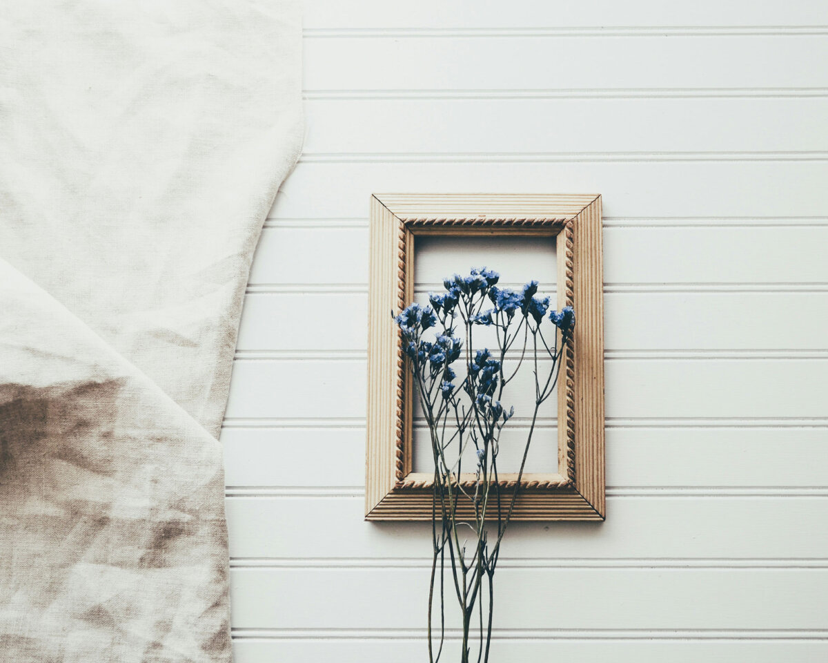 Holzrahmen mit blauen getrockneten Blumen auf weiÃer Wand