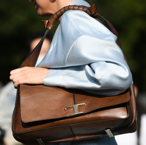 Farbkombinationen Trends 2025: Braun wird zu Hellblau kombiniert. Eine Frau trÃ¤gt eine braune Schultertasche zu einer hellblauen Satinbluse.