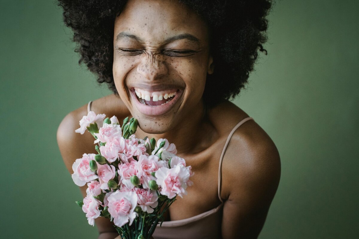 Eine Frau die einen rosa BlumenstrauÃ in HÃ¤nden hÃ¤lt und lacht